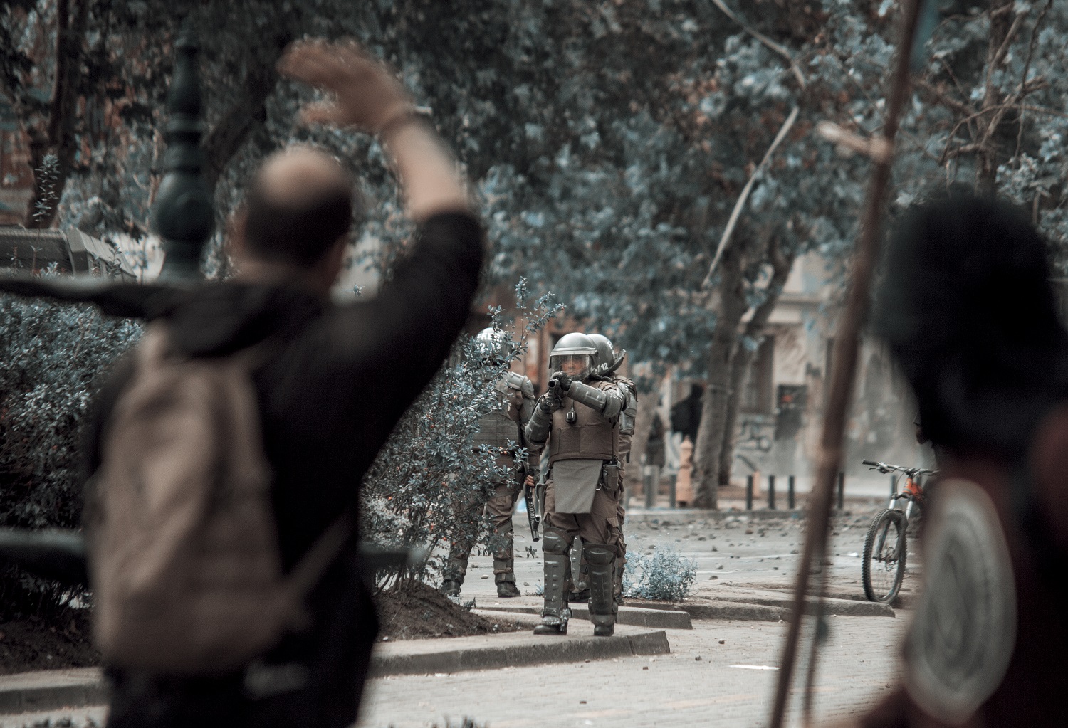 Funcionario de Carabineros apunta con su carabina lanzagases a manifestantes durante las protestas | Foto: José Miguel Araya, @josemiguelaraya